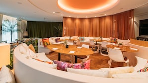 A modern hotel lobby with a round dining table, white sofas, and a large TV screen. - The Standard, Ibiza (Ibiza Town)