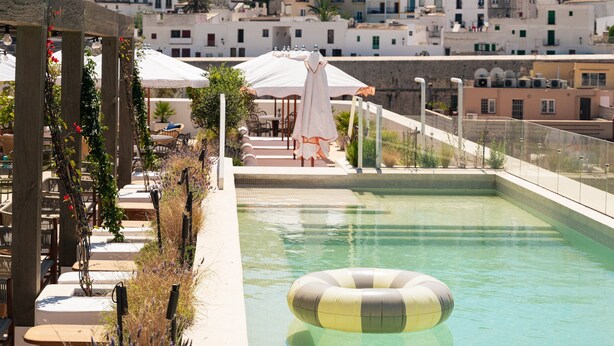 A pool area with a view of a historic town, including a prominent tower. - The Standard, Ibiza (Ibiza Town)