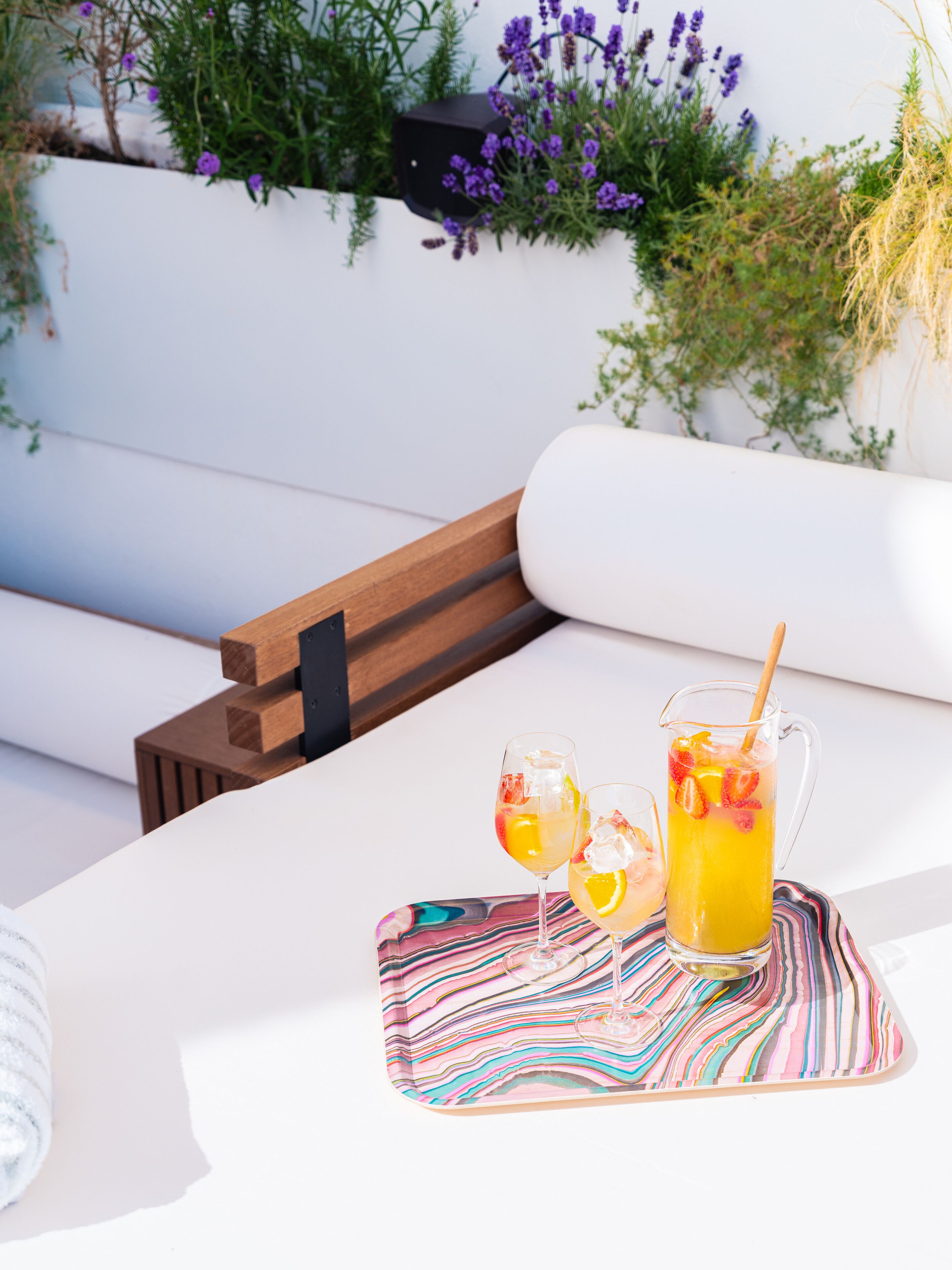 A white outdoor seating area with a wooden bench and a colorful striped placemat.