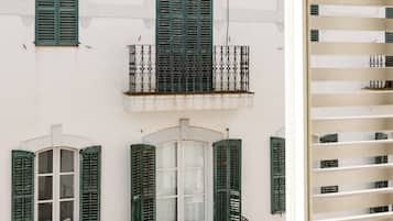 A white building with green shutters and balconies.