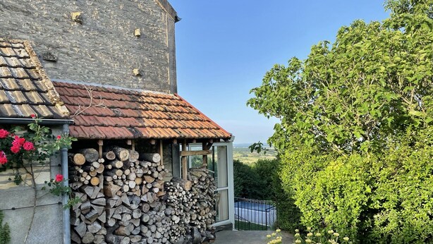 A rustic building with a stone exterior, a tiled roof, and a stack of firewood. - Large bright house with panoramic view (Saizy)