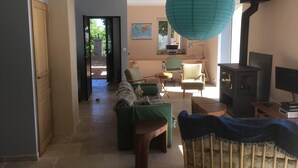 A living room with a green sofa, a wooden bench, a green armchair, a wooden table, a TV, and a fireplace. - Large bright house with panoramic view (Saizy)