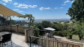 A terrace with a view of the countryside, a table with chairs, and a hanging plant. - Large bright house with panoramic view (Saizy)