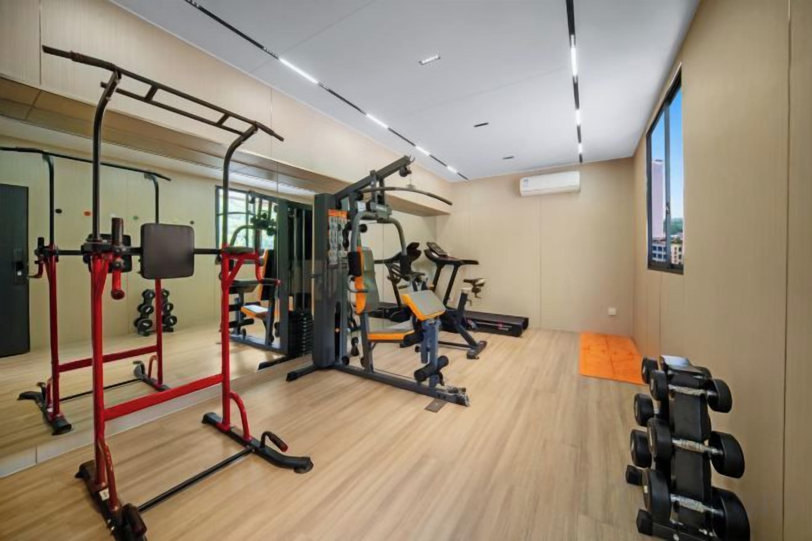 Une salle de sport équipée de divers appareils d’exercice, d’un miroir et d’une fenêtre donnant sur un paysage agréable.