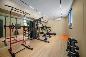 Un gimnasio con diferentes equipos de ejercicio, un espejo y un ventanal con vistas.
