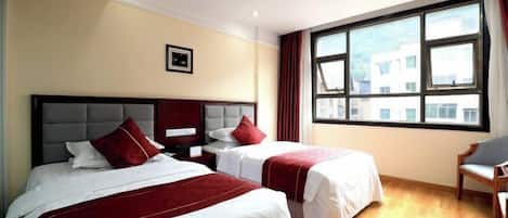 Une chambre d’hôtel avec deux lits, une fenêtre avec des rideaux, une chaise et un tableau encadré au mur.