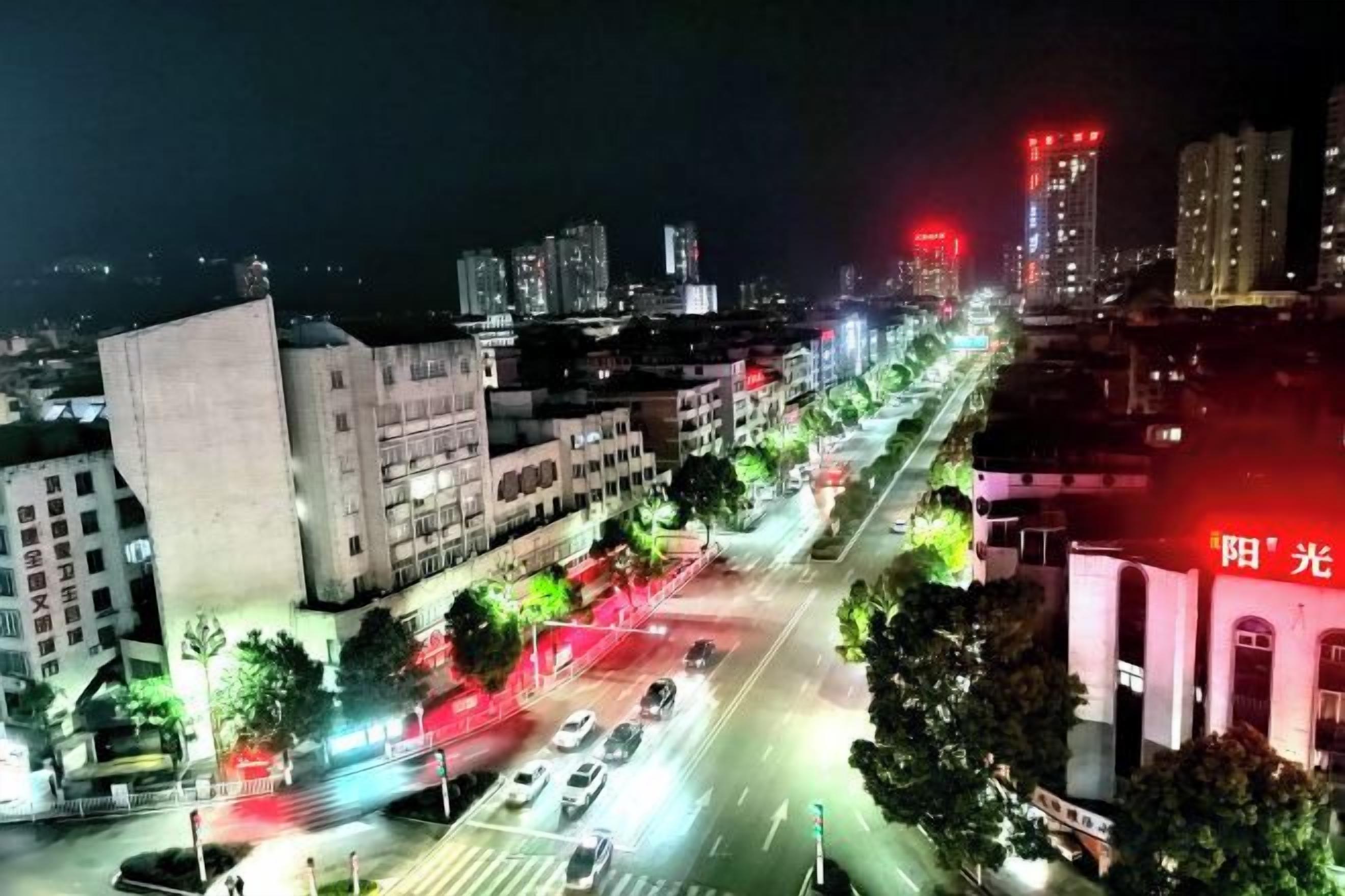 A nighttime cityscape with illuminated buildings and a busy street.