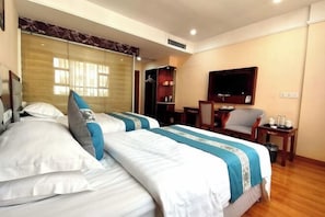 A hotel room with two beds, a desk, a chair, a TV, and a wardrobe. - Zhenghua Hotel (Zunyi)