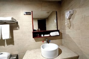 A bathroom with a round sink, a mirror, a towel rack, and a hairdryer on the wall. - Zhenghua Hotel (Zunyi)