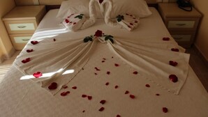 Una cama impecable con pétalos de rosa y una decoración de toallas con forma de corazón.