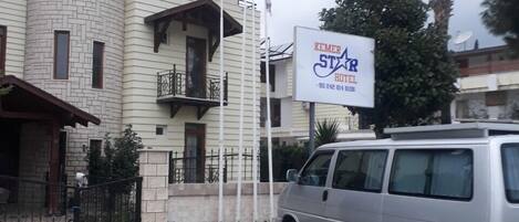 A building with a sign for 'Kemer Star Hotel' and a parked van in front.