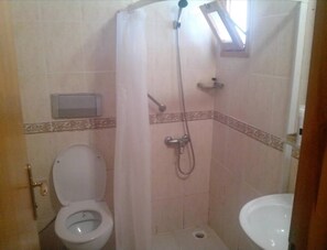A small bathroom with a toilet, shower, and sink.
