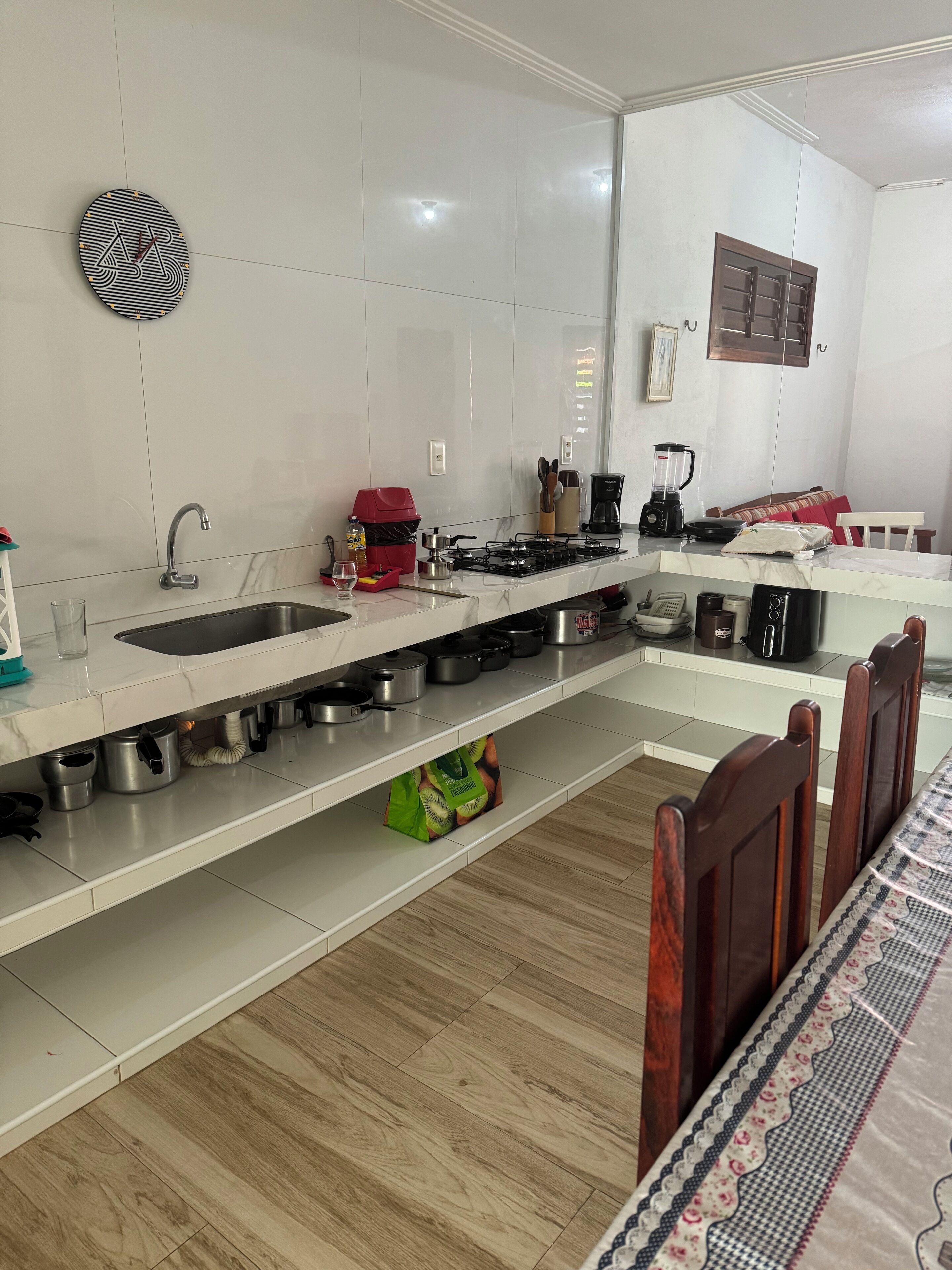 Eine moderne Küche mit weißer Arbeitsplatte, Edelstahlgeräten und einem Holztisch.