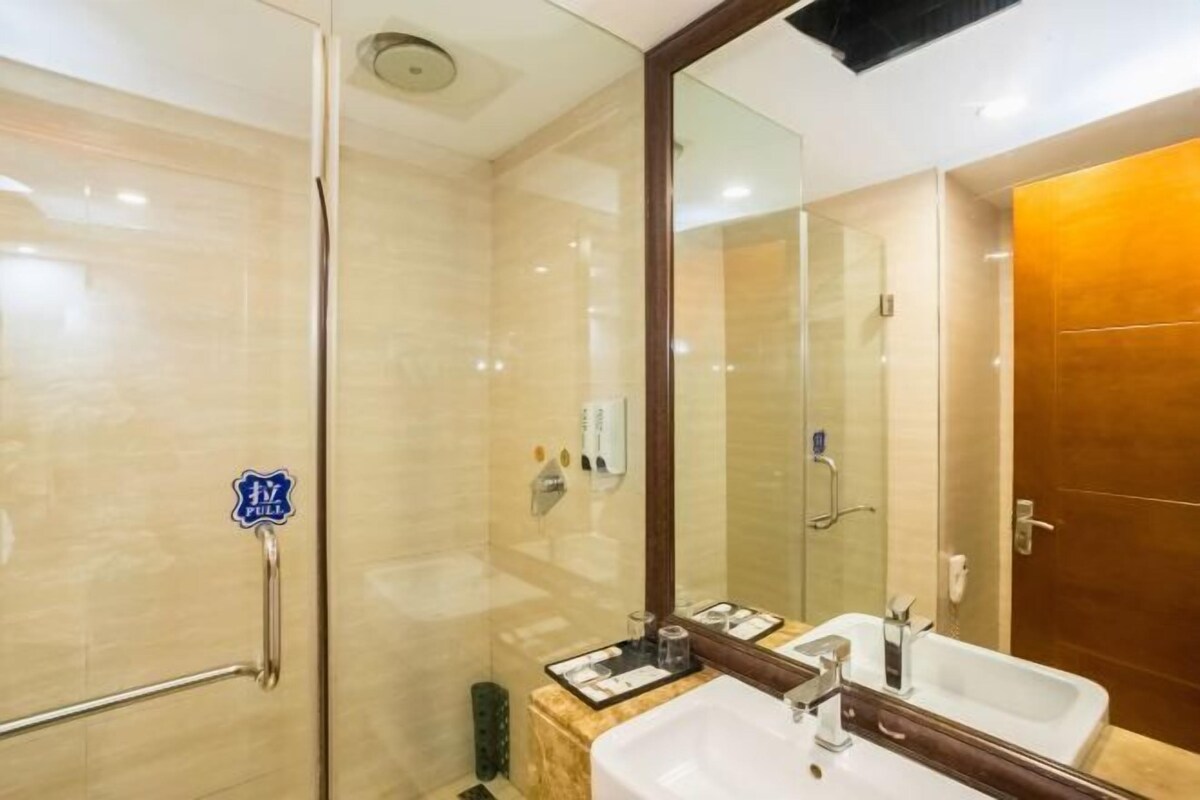 A modern bathroom with a glass shower enclosure, a large mirror, and a dual sink vanity.