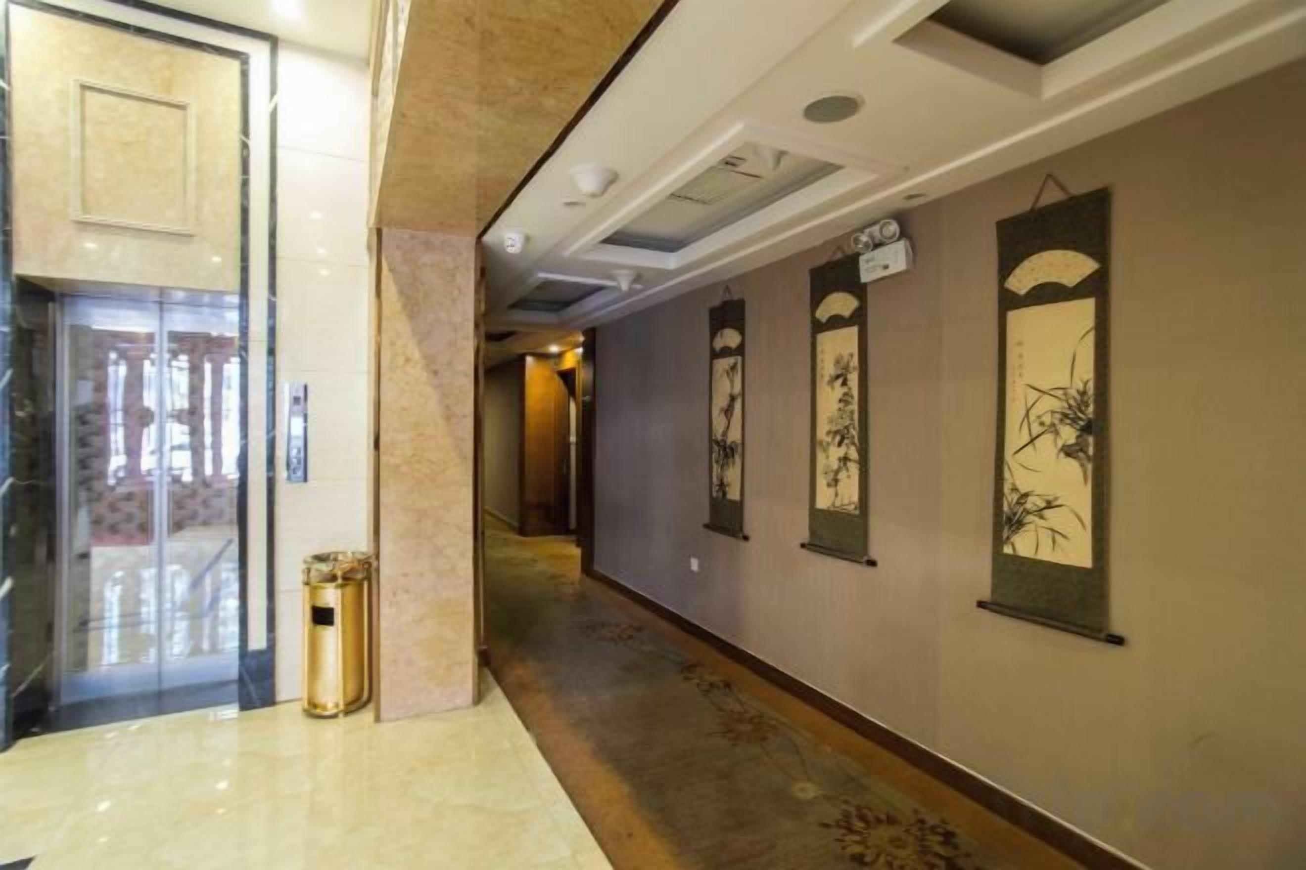 Un pasillo con piso de mármol, un cesto de basura y obras de arte en la pared.