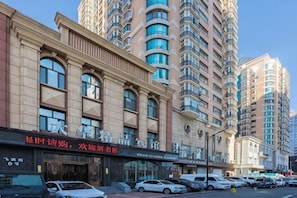 A multi-story hotel with a classic facade, large windows, and a parking lot in front. - Dahua Boutique Hotel (Harbin Exhibition Center) (Harbin)