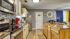 Una cocina con electrodomésticos de acero inoxidable, armarios de madera, horno empotrado y una barra desayunadora.