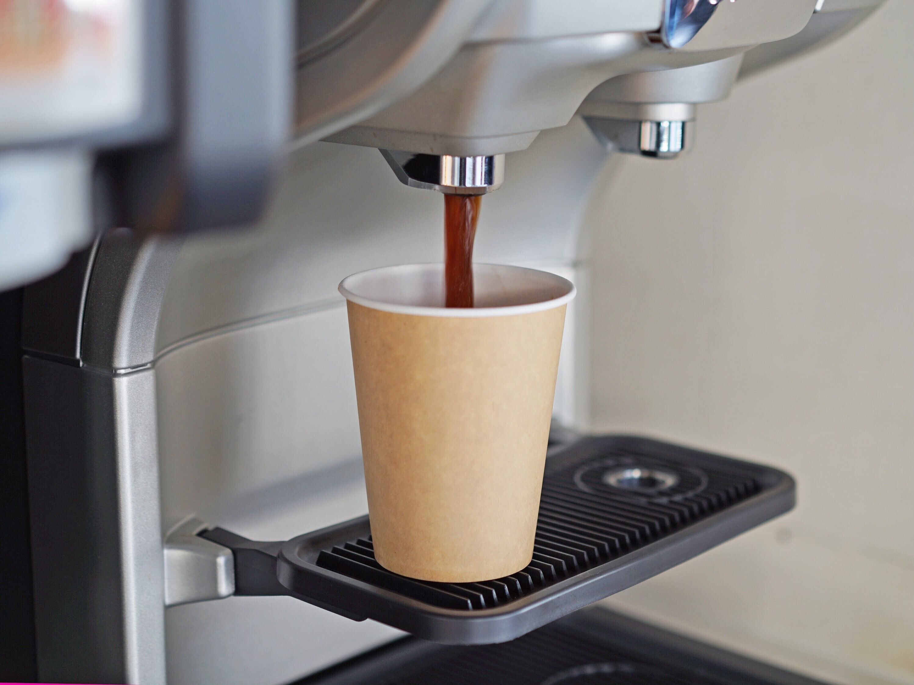 A paper cup under a coffee machine.