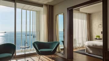 Quarto de hotel moderno com uma varanda ampla, uma cama, uma mesa pequena e uma cadeira.