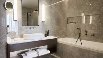 Une salle de bain moderne avec un grand miroir, un lavabo blanc, un meuble-lavabo foncé et une baignoire.