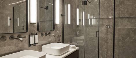 A modern bathroom with two sinks, a glass shower enclosure, and a large mirror.