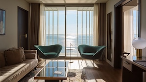 A modern hotel room with a large window, two green armchairs, a sofa, a glass coffee table, and a desk with a lamp. - ON Residence (Thessaloniki)