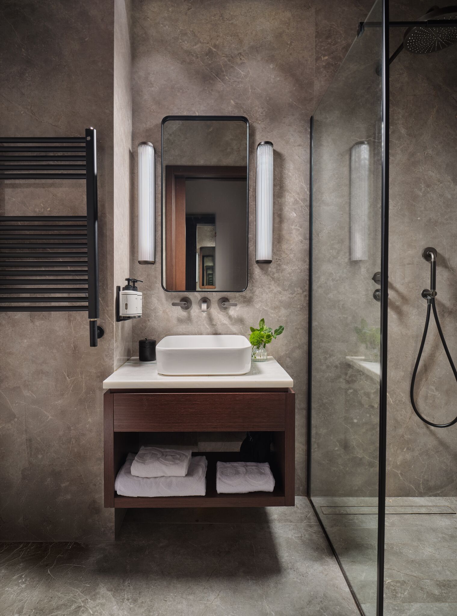Une salle de bain avec un grand miroir, un lavabo, une douche et un porte-serviettes.
