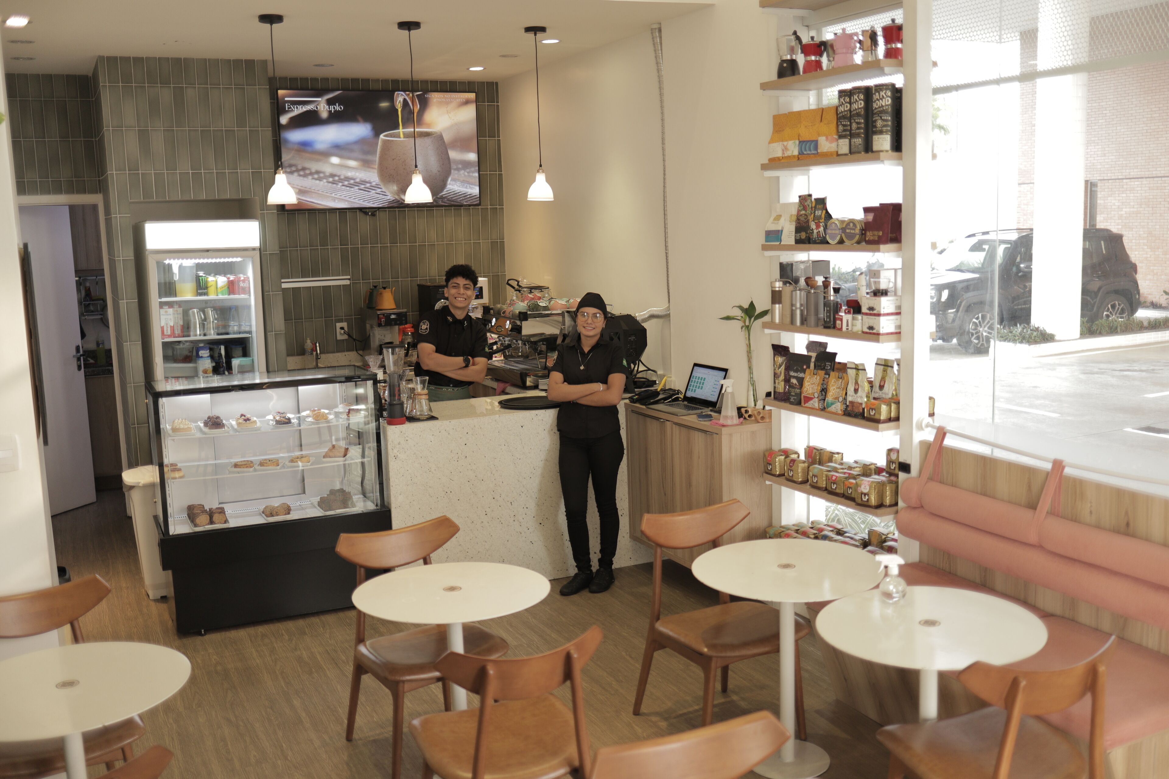 Una cafetería con mostrador, vitrina y zona de estar.