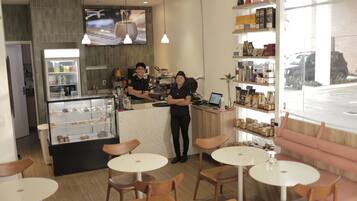 Una cafetería con mostrador, vitrina y zona de estar.
