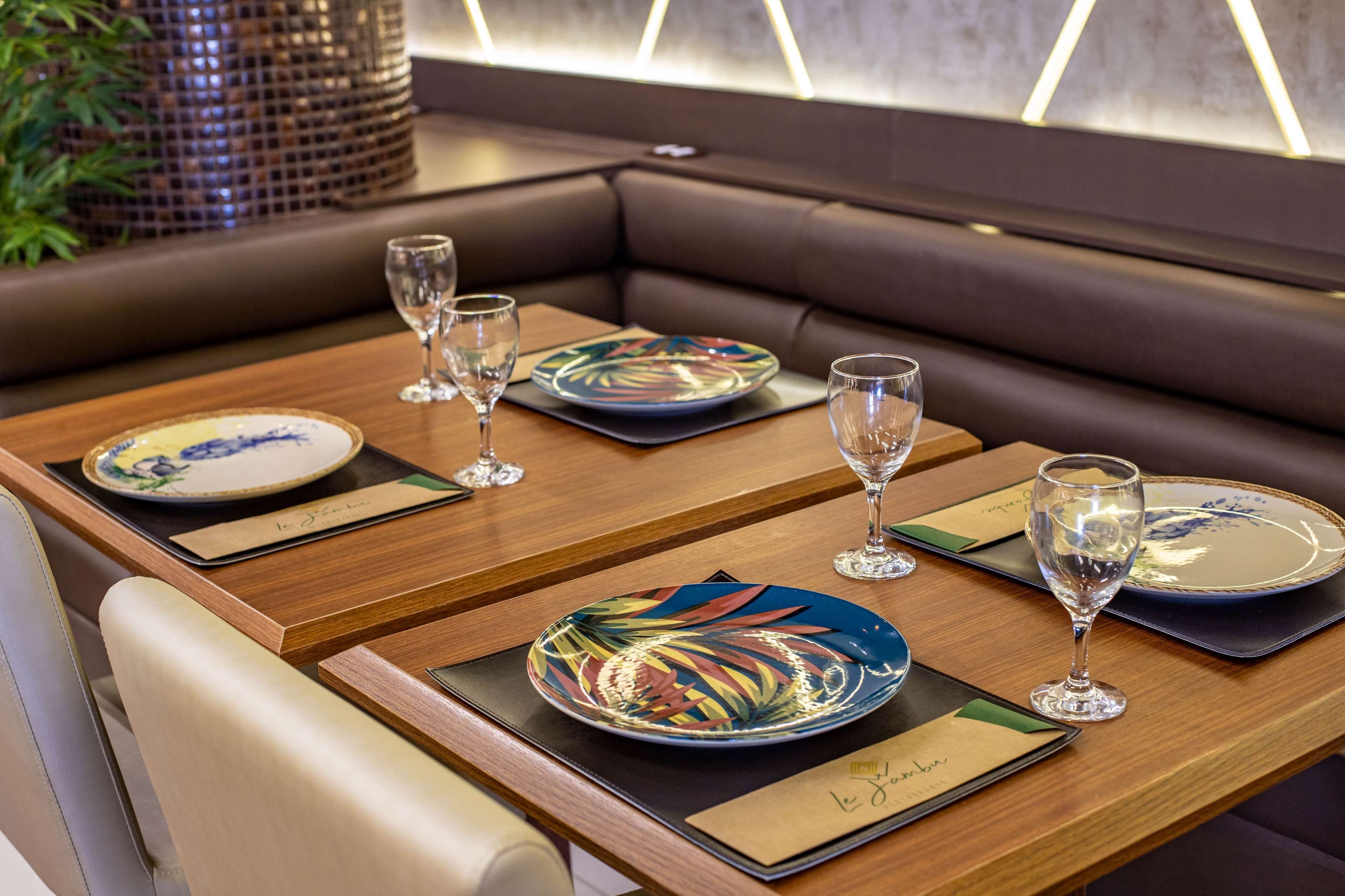 A dining area with a booth seating arrangement, wooden tables, and glassware.