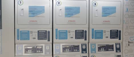 Tres lavadoras autoservicio OMO con instrucciones y códigos QR.