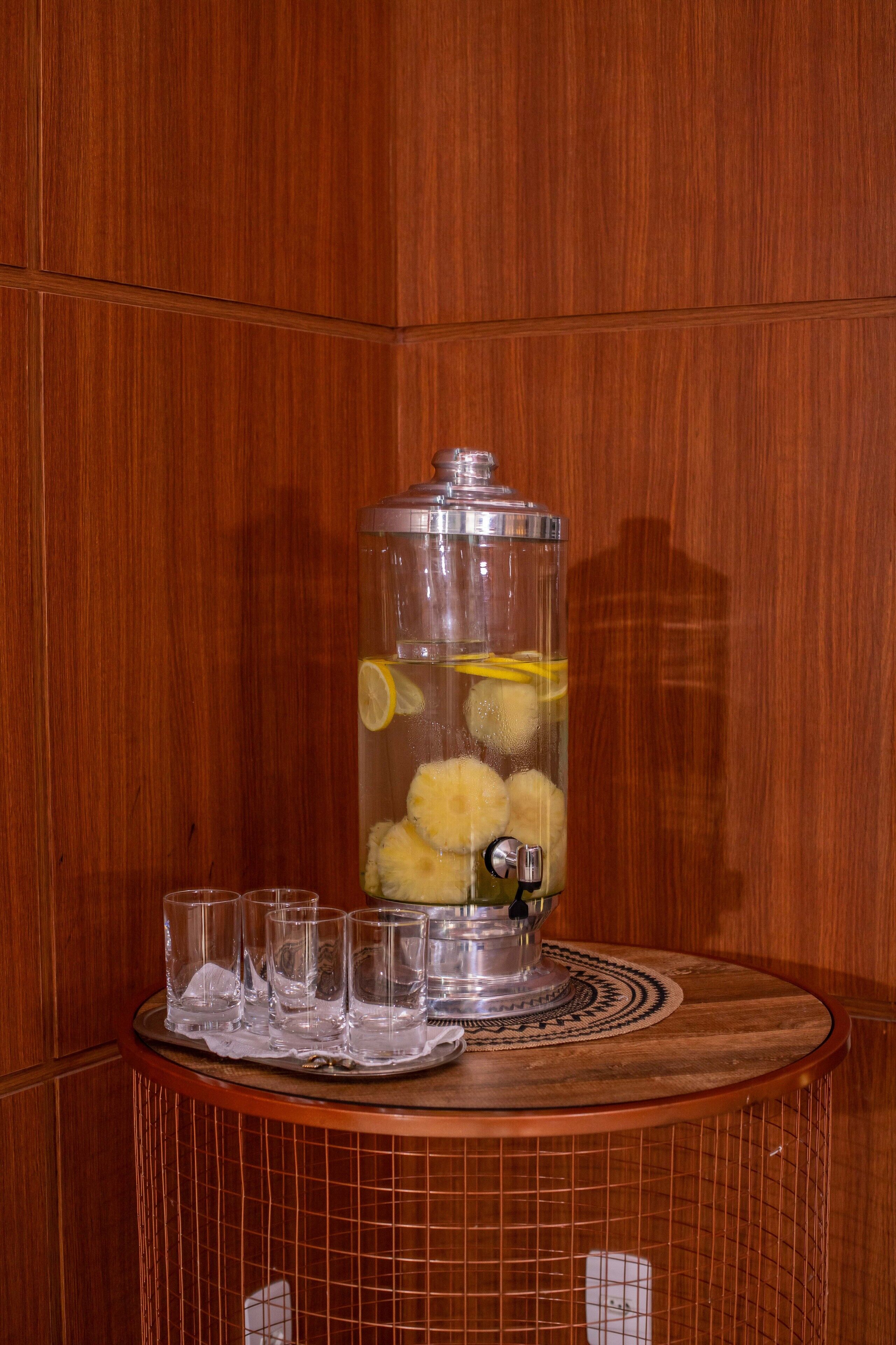 Un distributeur de boissons doté d’un récipient transparent, de citrons et de glaçons.