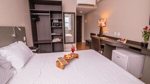 A hotel room with a bed, a desk, a mini-fridge, a microwave, and a wardrobe. - Ramada by Wyndham Manaus Torres Center (Manaus)