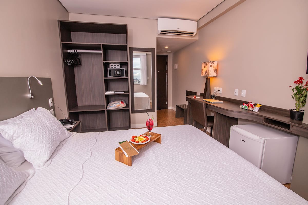 A hotel room with a bed, a desk, a mini-fridge, a microwave, and a wardrobe.
