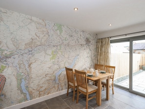 A dining area with a large wall map, wooden table, chairs, and a glass door leading outside.