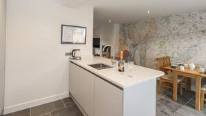Una cocina moderna con una isla central, un comedor con mesa de madera y un mapa en la pared.