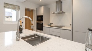 Una cocina moderna con un lavaplatos de acero inoxidable, horno doble y campana extractora integrada.