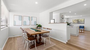 Une cuisine moderne avec des meubles blancs, un plan de travail en bois et une chaise bleue.