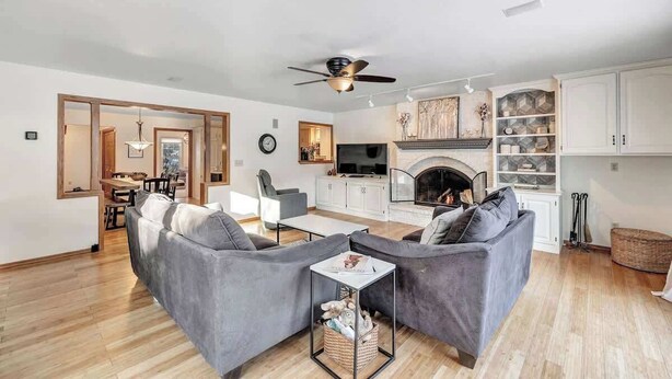 A modern living room with a fireplace, grey sofas, and a dining area.