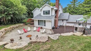 A two-story house with a backyard patio area featuring outdoor seating and a fire pit.