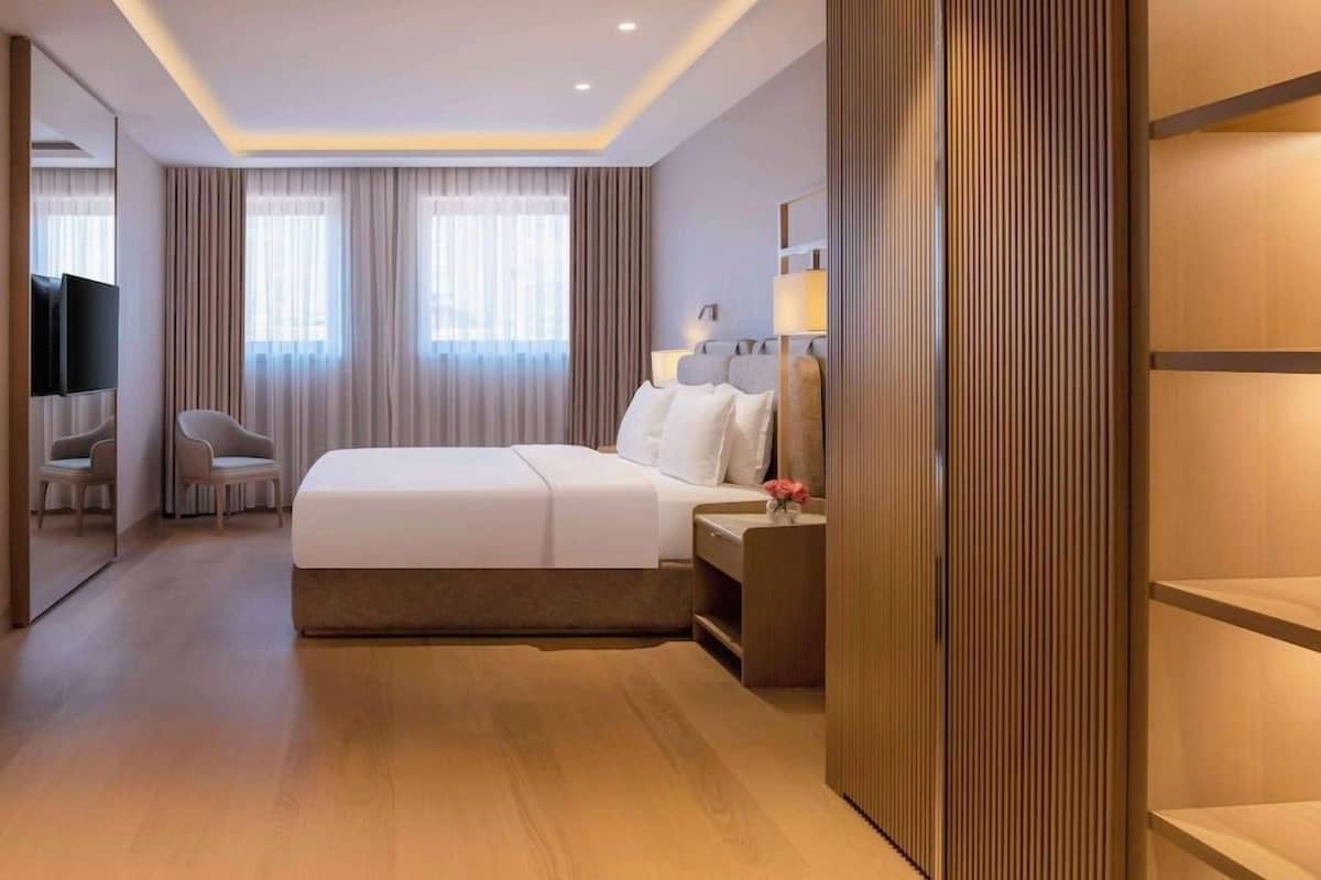 A hotel room with a bed, bedside table, lamp, and a mirror.