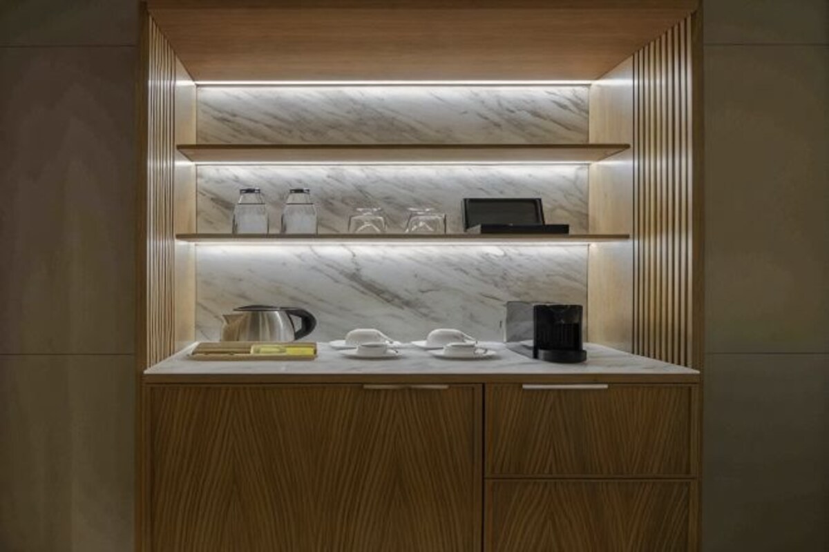 A kitchen with wooden cabinets, a marble backsplash, and a countertop with kitchenware.