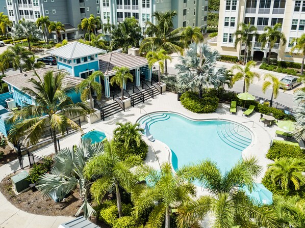 Un resort con piscina rodeada de palmeras y un edificio azul.