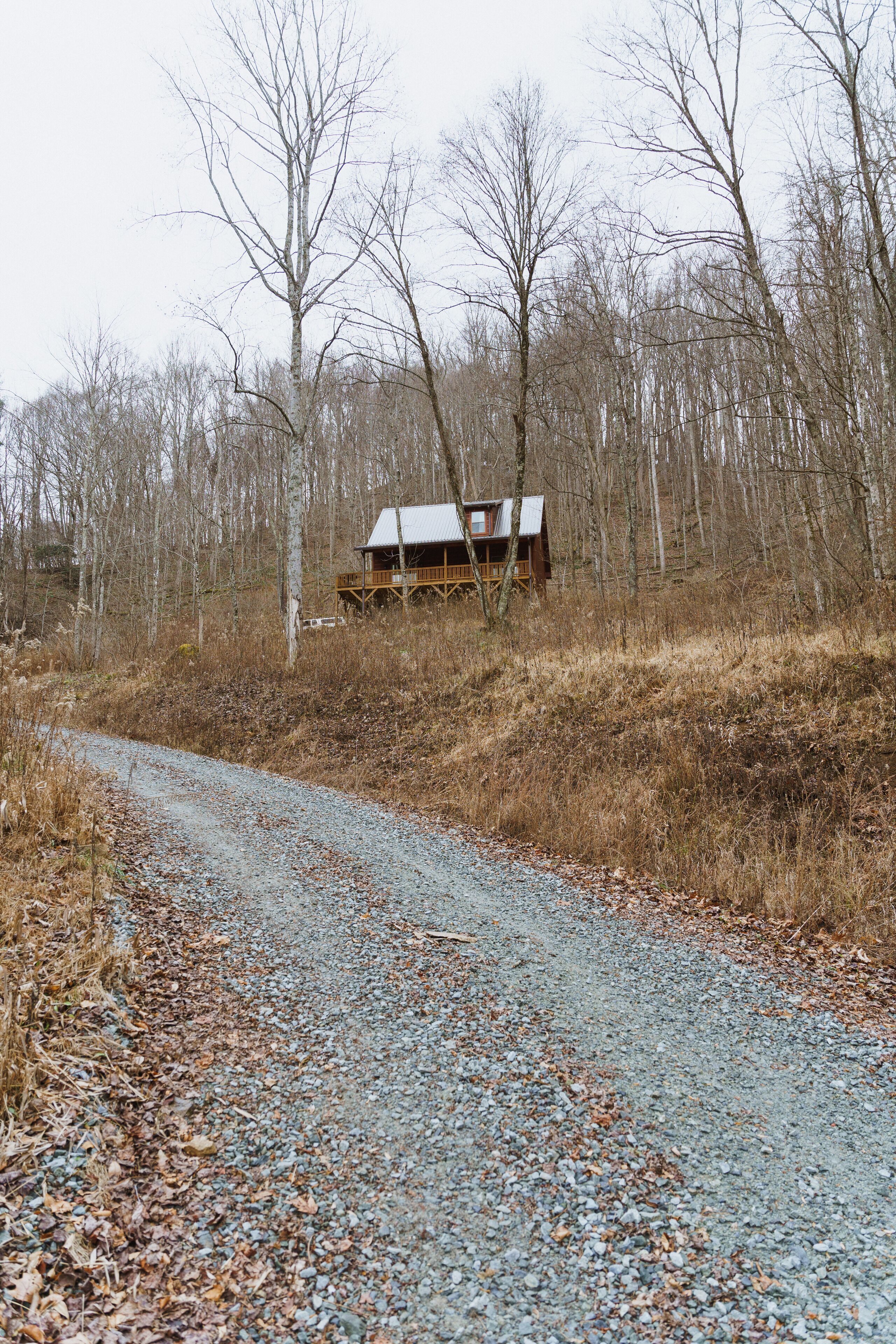 Eine rustikale Holzhütte in einem Waldgebiet, mit einem Schotterweg, der dorthin führt.