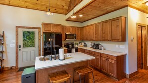 A kitchen with wooden cabinets, a white countertop, and a stainless steel refrigerator.