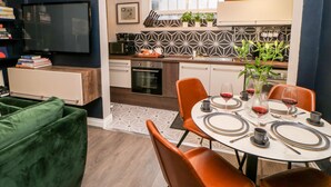 A modern kitchen with a dining area, featuring a round table set for two with wine glasses and plates. - Jaipur House (Richmond)