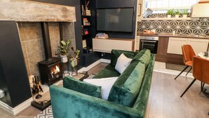 A modern living room with a fireplace, green sofa, and a TV mounted on the wall. - Jaipur House (Richmond)