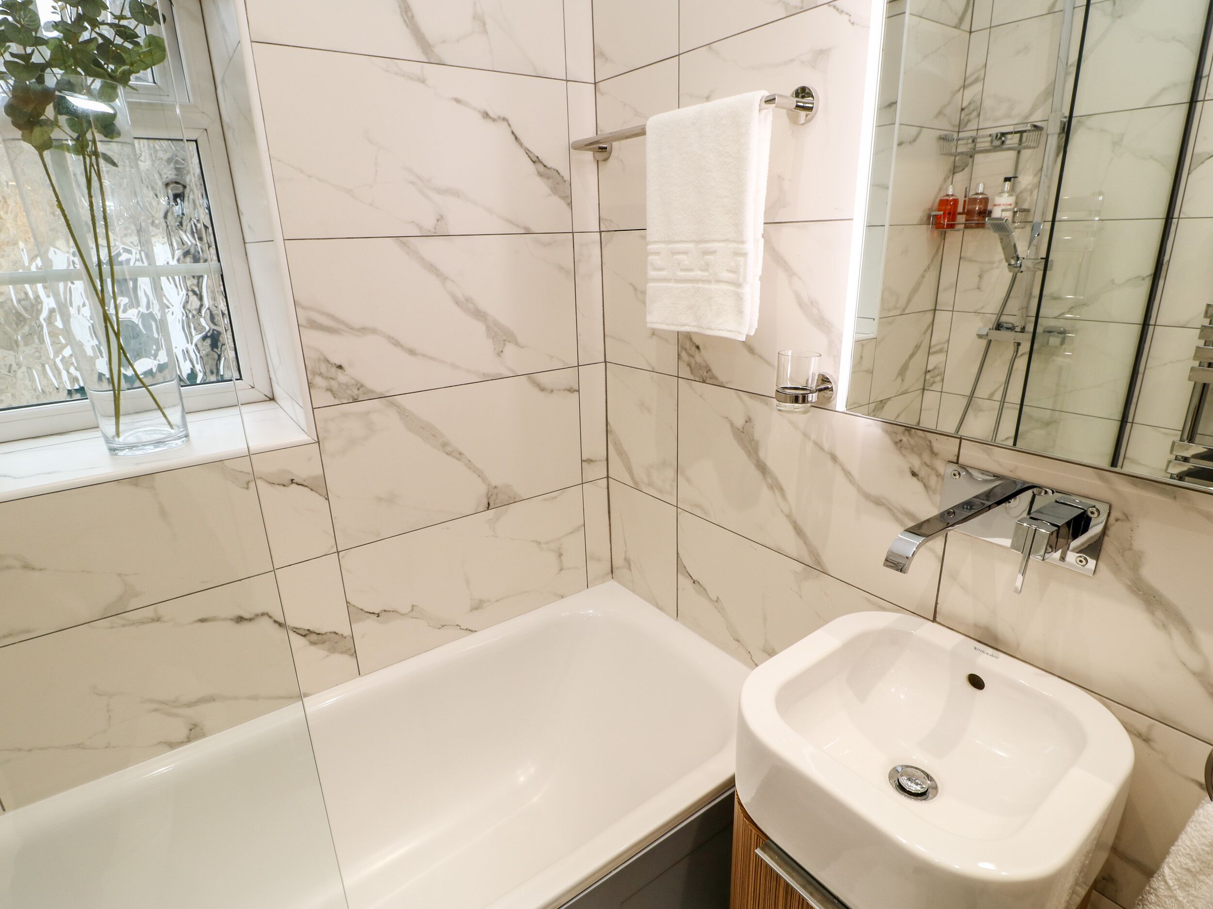 A bathroom with a bathtub, a sink, and a mirror.