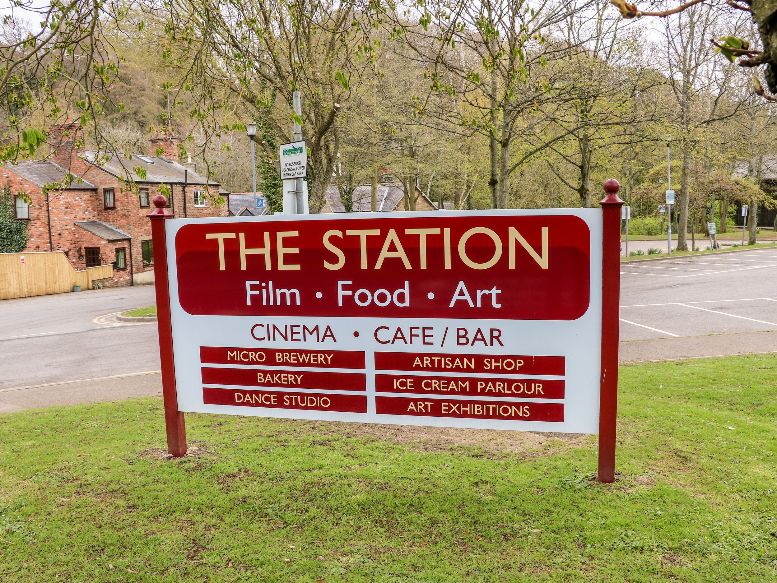 Letrero de 'The Station' que anuncia servicios como cine, cafetería/bar, microcervecería, panadería, estudio de baile, tienda de artesanías, heladería y exposiciones de arte.