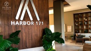 A reception area with a wooden wall, a large 'HARBOR 171' sign, and a seating area with a bookshelf and a plant. - Harbor Puerto Vallarta 1008 (Puerto Vallarta)